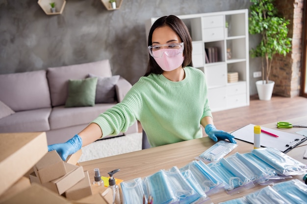 Foto de dama china manos guantes de látex negocios organizar orden facial máscaras médicas empaquetado hecho a mano clasificación cajas de cartón tienda de entrega en línea gerente de comercio oficina en casa en el interior