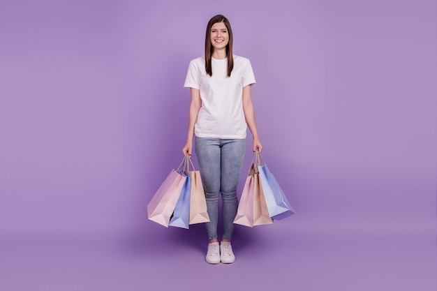 Foto de dama encantadora llevar paquetes de compras fondo violeta aislado