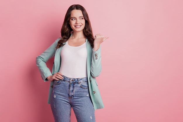 Foto foto de la dama promotora en traje de moda mirada directa al lado del dedo espacio vacío sobre fondo rosa