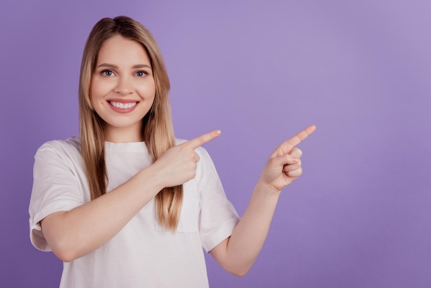 Foto de alegre promotora senhora dedos diretos espaço vazio usar roupas casuais em fundo roxo