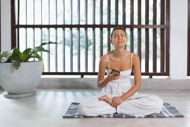 Foto de alta qualidade de uma mulher triste usando o telefone durante uma postura difícil de ioga