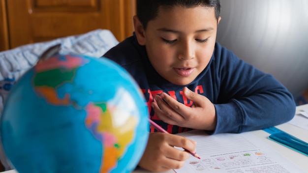 Foto de alto ângulo de uma criança hispânica estudando em casa