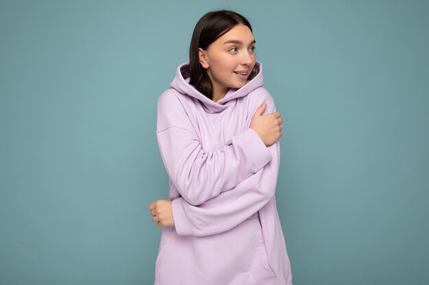 Foto de atraente feliz sorridente jovem vestindo roupa casual em pé isolado sobre um fundo colorido com um espaço vazio, olhando para o lado.