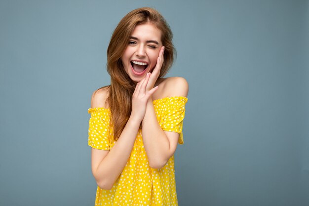 Foto de atraente fofa feliz emocional jovem posar isolado na parede do fundo com