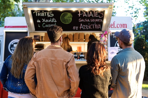 Foto de atraente jovem grupo de amigos que visitam o mercado de comida na rua.