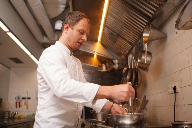 Foto de baixo ângulo de um chef batendo o molho em uma tigela, cozinhando no restaurante