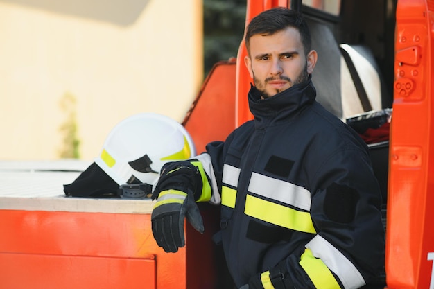 Foto de bombeiro com máscara de gás e capacete perto do carro de bombeiros