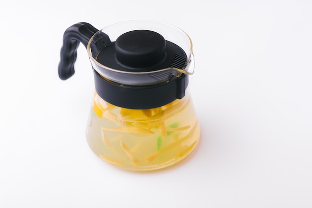Foto de bule de chá com limão e hortelã sobre superfície branca