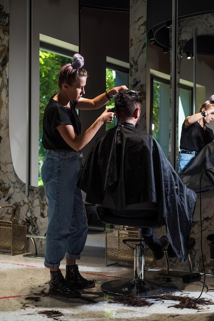 Foto de cabeleireiro cortando cabelo de cliente hipster bonito Cabeleireiro atendendo cliente na barbearia