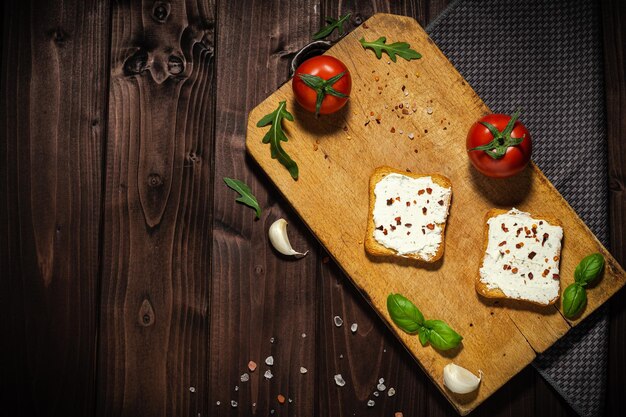 Foto de café da manhã de cream cheese e pão fatiado de tomate em fundo de madeira