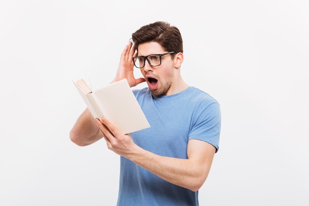 Foto de cara intelectual usando óculos lendo livro de indignação, isolado sobre a parede branca