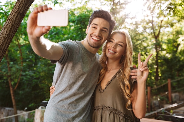 Foto de casal adorável alegre posando juntos e fazendo selfie