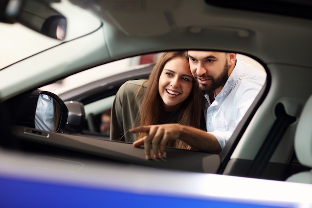 Foto de casal adulto escolhendo carro novo no showroom