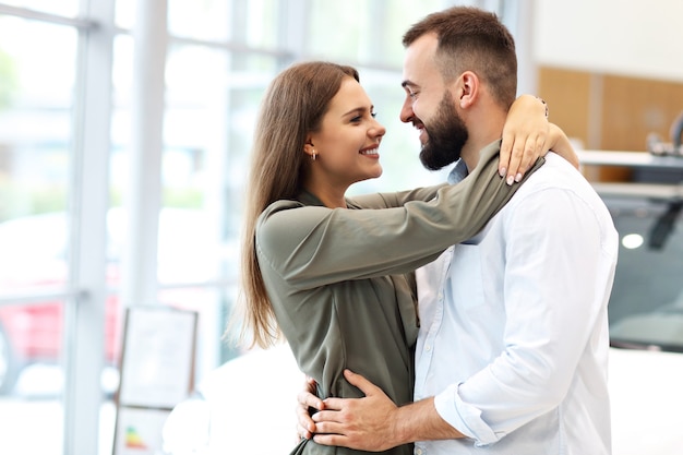 Foto de casal adulto escolhendo carro novo no showroom