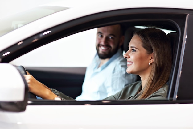 Foto de casal adulto escolhendo carro novo no showroom