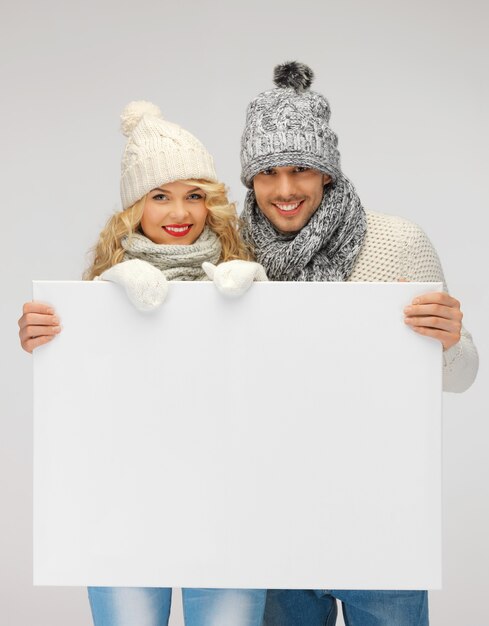 foto de casal de família com roupas de inverno segurando um quadro em branco