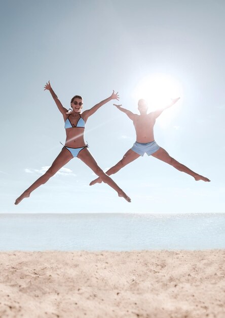 Foto de casal feliz pulando na praia