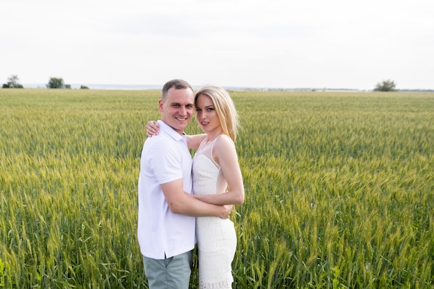 Foto de casal feliz se abraçando no campo de trigo