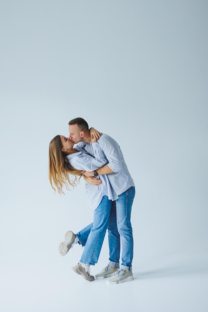 Foto de casal feliz vestindo camisas brancas jeans azul isolado fundo branco Um homem e uma mulher estão se abraçando em um fundo branco