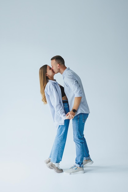 Foto de casal feliz vestindo camisas brancas jeans azul isolado fundo branco um homem e uma mulher estão se abraçando em um fundo branco