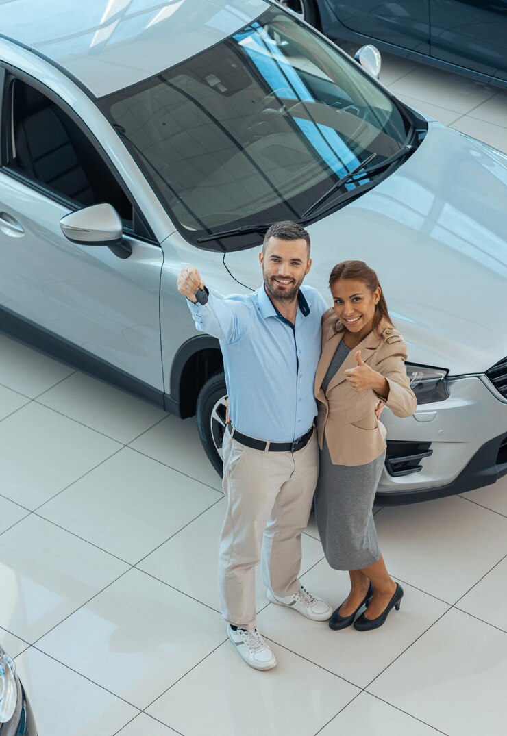 Foto de cima de um casal feliz comprando um carro novo em um salão de automóveis