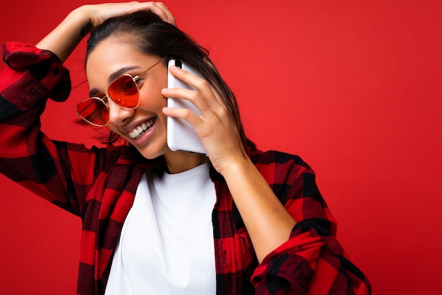 Foto de close de atraente sorridente jovem morena vestindo uma elegante camisa vermelha branca