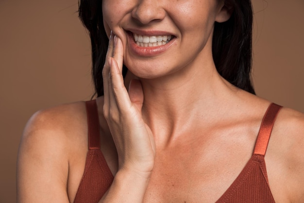 Foto de close de jovem fofa sentindo dor de dente e sofrendo com uma expressão infeliz, isolada em um fundo de cor bege