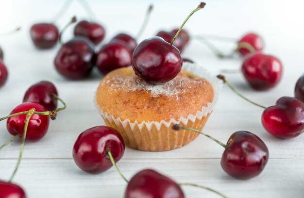 Foto de close de um muffin com cerejas na superfície branca