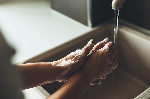 Foto de close de um procedimento de lavagem das mãos com sabão durante uma situação de pandemia