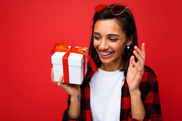 Foto de close de uma mulher morena adulta sorridente e atraente, isolada em uma parede de fundo vermelho