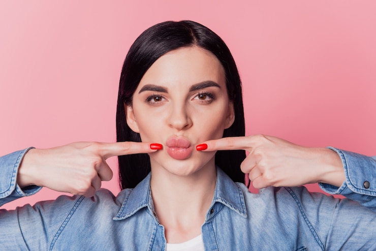 Foto foto de close de uma senhora muito engraçada apontando figners lábios fazendo beicinho enviando beijos no ar isolado fundo de cor rosa brilhante