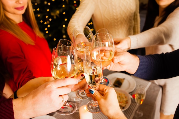 Foto de close-up cortada de copos com champanhe. Jovens brindando para celebrar o Natal ou Ano Novo