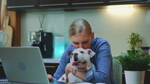 Foto de close-up da mulher alegre, abraçando o cachorro pequeno na cozinha