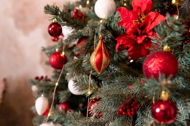 Foto de close up de bolas festivas na árvore do abeto na sala de estar com decorações de Natal vermelhas brancas penduradas ...