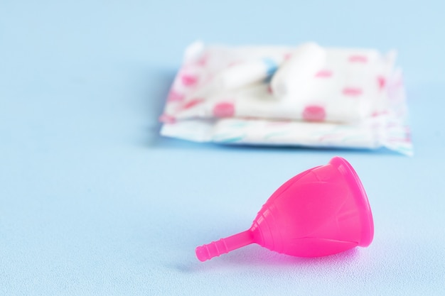 Foto de close up de copo menstrual e absorvente higiênico na mesa