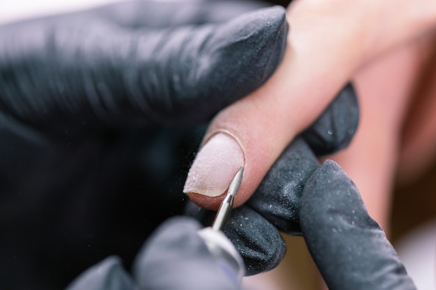 Foto de close-up de manicure de hardware em um salão de beleza. Manicure aplicando lima de unha elétrica