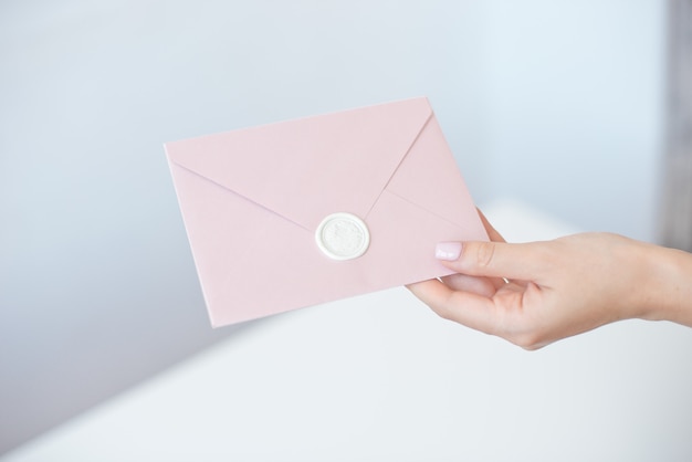 Foto de close-up de mãos femininas segurando um envelope de convite com um selo de cera, vale-presente, cartão postal, cartão de convite de casamento.