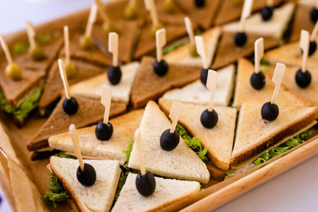 Foto de close-up de um sanduíche de clube. sanduíche com presunto, presunto, salada, legumes, alface e azeitonas em um pão de centeio fresco fatiado