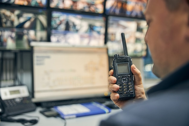 Foto de close-up de um walkie-talkie sendo usado para comunicar instruções da sala de controle