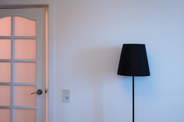 Foto de close-up de uma lâmpada de loft elegante na parte superior e na porta com interruptor de luz na sala perto da saída do apartamento