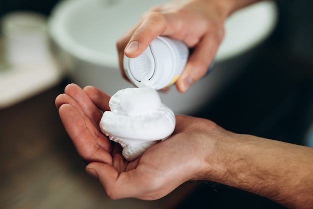 Foto de close-up jovem puxando espuma na mão no banheiro de manhã cedo