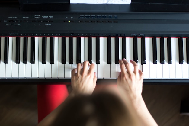 Foto de close-up superior da mão de um artista de música clássica tocando piano ou sintetizador eletrônico (teclado de piano)