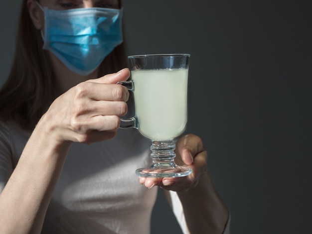 Foto de close-up vista das mãos femininas segurando um copo de água. Jovem mulher tomando medicação, sentindo-se doente.