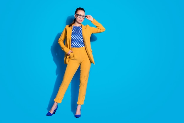 Foto de corpo inteiro de atraente mulher de negócios bem-sucedida trabalhador segurar mão visão leitura óculos usar terno blazer amarelo camisa de blusa pontilhada isolada fundo de cor azul brilhante