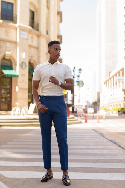 Foto de corpo inteiro de jovem empresário africano caminhando ao ar livre na faixa de pedestres