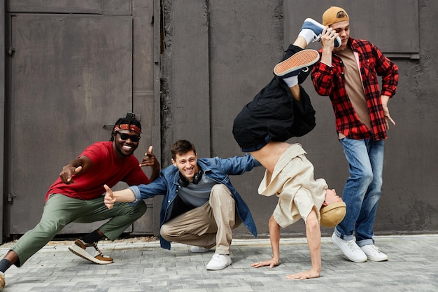 Foto de corpo inteiro de toda a equipe masculina de hiphop posando ao ar livre e olhando para a câmera