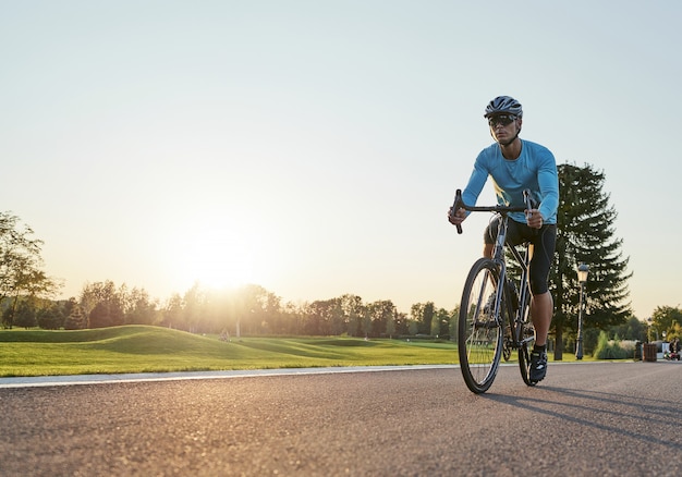 Foto de corpo inteiro de um ciclista profissional em roupas esportivas e treinamento de capacete de proteção