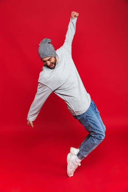 Foto de corpo inteiro de um homem alegre de 30 anos em roupa casual sorrindo e pulando isolado