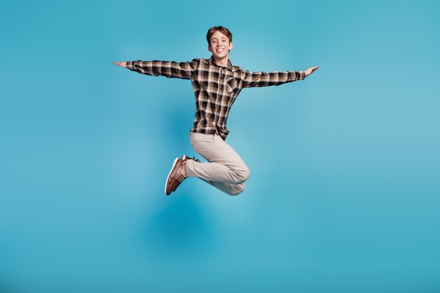 Foto de corpo inteiro de um jovem jumper de bom humor alegre mãos voar avião isolado no fundo de cor violeta