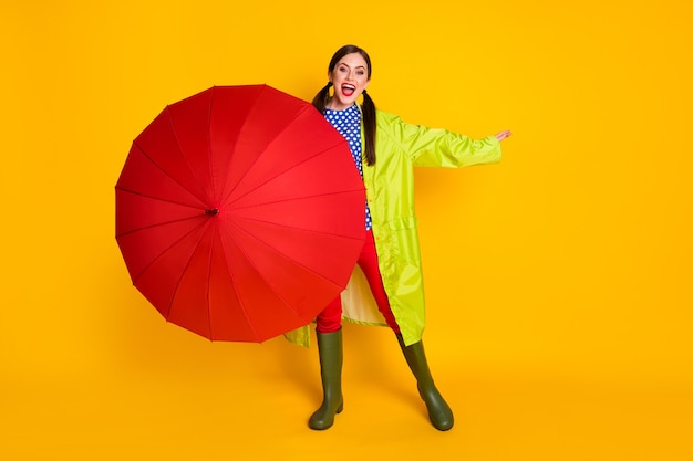 Foto de corpo inteiro de uma garota entusiasmada fechar a capa guarda-sol vermelho desfrutar de caminhada chuvosa de primavera usar calças vermelhas calças esportivas isoladas sobre fundo de cor brilhante brilhante